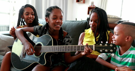 Casual black African family bonding thogether through music guitar. Daughter playing musical instrument