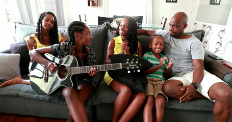 Casual black African family bonding thogether through music guitar. Daughter playing musical instrument
