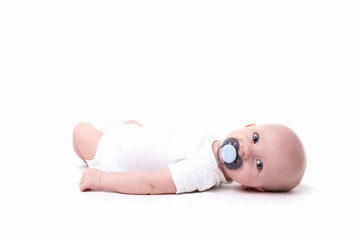 baby with a pacifier in his mouth on a white isolated background looks at the camera