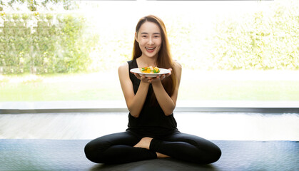 asian woman hold dish of healthy pizza in yoga suite in healthy yoga