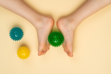 green needle ball for massage and physiotherapy on a beige background with the image of a child's foot, the concept of prevention and treatment of hallux valgus