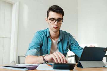 A young man manages finances from home. Economist works at home, freelance.