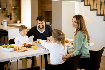 Young happy family talking while having breakfast at dining table
