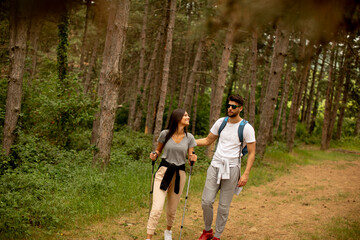 Couple of hikers with backpacks walk through the forest