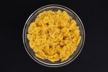 bowl of farfalle pasta on black background, top view
