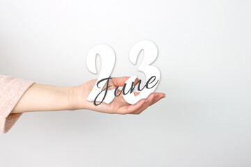 June 23rd. Day 23 of month, Calendar date. Calendar Date floating over female hand on grey background. Summer month, day of the year concept.