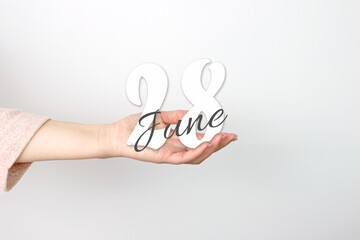 June 28th. Day 28 of month, Calendar date. Calendar Date floating over female hand on grey background. Summer month, day of the year concept.