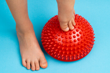 children's feet with a red balancer on a light blue background, treatment and prevention of flat...