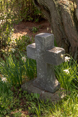 An old cross shaped tombstone next to a tree