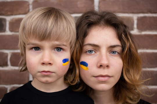 faces of  boy and young woman with  blue and yellow flag painted on cheeks. Family, unity, support. Ukrainians are against the war. asking for help from the world community. Stand with ukraine