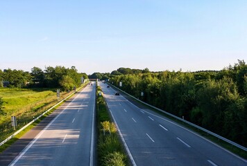 Perspective view of highway in Itzehoe, Germany with trees and clear blue sky background.