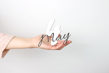 May 4th. Day 4 of month, Calendar date. Calendar Date floating over female hand on grey background....