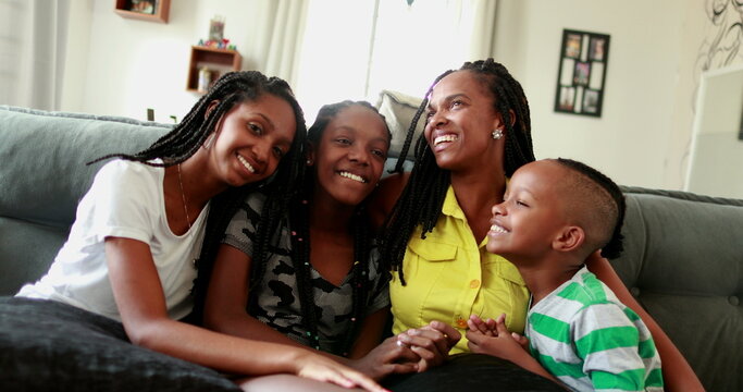 Black African mother and teen daughters and little boy son together at home sofa