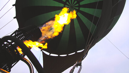 Adventure on hot air balloon watermelon. Burner directing flame into envelope. The aircraft fly in morning blue sky due to hot air. Hot air burning gas fire to air balloon or aerostat during flight.