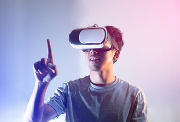 Young man wearing the virtual reality goggles and hand up to touch something