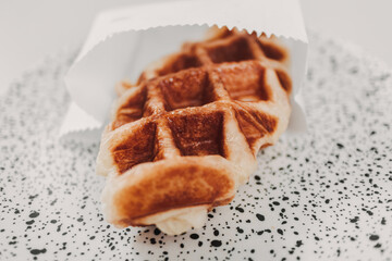 Close up small piece of homemade waffle on white dots dish.