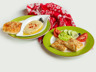 Turkish assorted food Houmus With Pita Bread, Peynirli Borek in a dish isolated on colorful table cloth top view on grey background