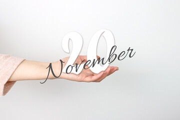 November 20th. Day 20 of month, Calendar date. Calendar Date floating over female hand on grey background. Autumn month, day of the year concept.