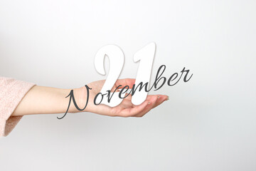 November 21st . Day 21 of month, Calendar date. Calendar Date floating over female hand on grey background. Autumn month, day of the year concept.