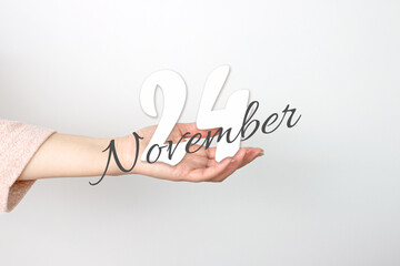 November 24th. Day 24 of month, Calendar date. Calendar Date floating over female hand on grey background. Autumn month, day of the year concept.