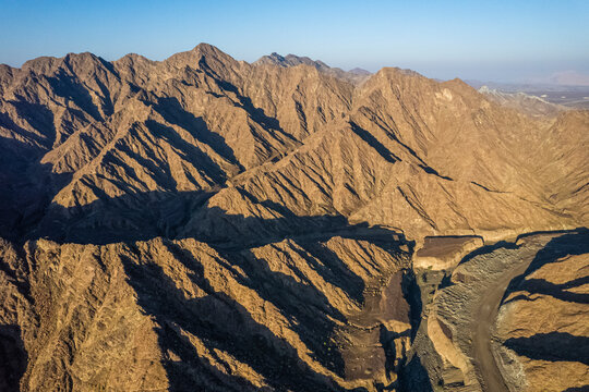Aerial view of a canyon among the rocky and dry mountains in the desert in Ajman State, United Arab Emirates.