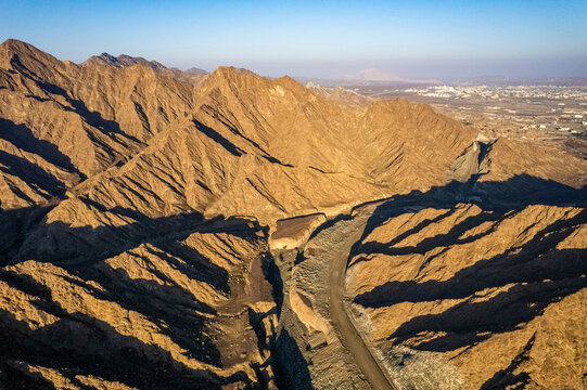 Aerial view of a canyon among the rocky and dry mountains in the desert in Ajman State, United Arab Emirates.