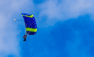 Sky diving parachutist decending against a blue sky