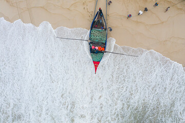 Aerial view of people along the shoreline prating the Arte Xavega, a Portuguese traditional fishing technique in Torreira, Portugal.