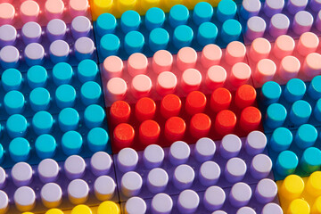 children's play background: the plane of plastic multi-colored bricks, blur, selective focus