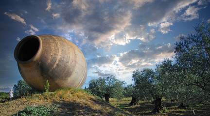 View on big clay amphora vase on hill at olive trees grove in rural french landscape with sun...