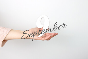 September 9th. Day 9 of month, Calendar date. Calendar Date floating over female hand on grey background. Autumn month, day of the year concept.