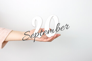 September 20th. Day 20 of month, Calendar date. Calendar Date floating over female hand on grey background. Autumn month, day of the year concept.