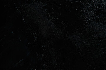 Dark creative background - rough linen canvas unevenly covered with black primer, reflections of light. Toning, blurring, selective focus.