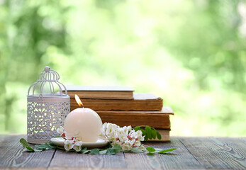 candle, flowers and books on table in garden, abstract green natural background. spring or summer...