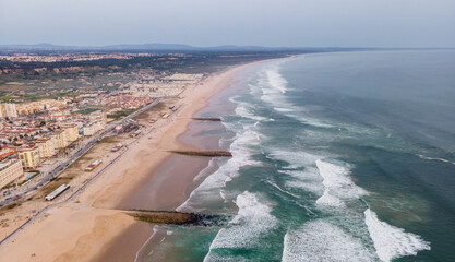 Aerial view of Costa da Caparica landscape at sunset, view of the majestic beach with rough Atlantic Ocean rolling on the shoreline, Setubal, Portugal.