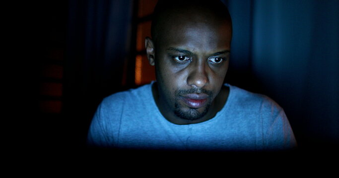 African Man Browsing Internet At Night In The Dark. Black Person Looking At Laptop Working Late