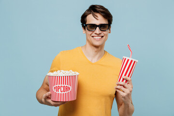 Young smiling fun man in 3d glasses watch movie film hold bucket of popcorn cup of soda pop...