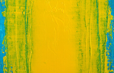 abstract bright colored background: a smeared flat wide spot of yellow paint on a blue fabric close up