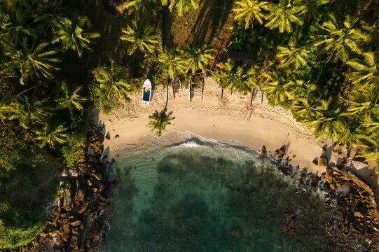 Aerial top down view of tiny secret beach with a small boat near the Indian ocean in Sri Lanka.