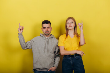 Two young beautiful people girl and guy standing on a yellow background.