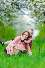 Fototapeta premium mother and daughter hugging against the backdrop of flowering trees