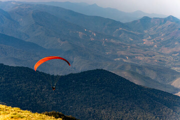 paisagem com uma pessoa praticando paraglider em descida das montanhas de Atibaia