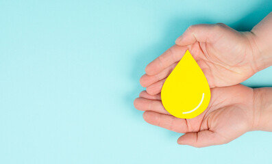 Holding a yellow drop, symbol for gas, petrol, diesel and oil, price increase caused by boycott, inflation, renewable energy