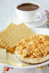 Colombian breakfast. Arepa (ground corn flour dough),egg with traditional sauce called hogado(stir-fried tomato and onion),with cup of chocolate, crackers and cheese,on light background. Close up. 