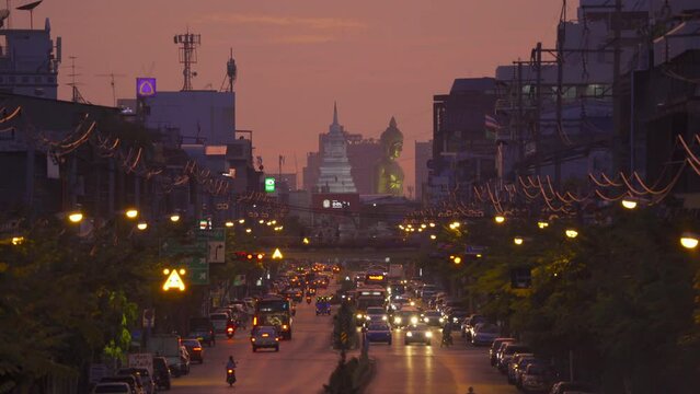 Aerial view of the Giant Golden Buddha in Wat Paknam Phasi Charoen Temple with cars on traffic street road in Phasi Charoen district, Bangkok. Urban town, Thailand. Downtown City.