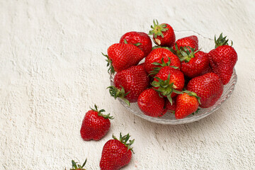 Ripe strawberries in a crystal bowl that stands on a white table