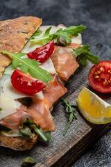 Sandwiches with homemade ciabatta bread, salted salmon fish, parmesan cheese, capers, cherry tomatoes and arugula, Restaurant menu, dieting, cookbook recipe top view