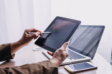 Business partnership coworkers using a tablet to chart company financial statements report and profits work progress and planning in office room.