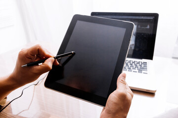 Business partnership coworkers using a tablet to chart company financial statements report and profits work progress and planning in office room.