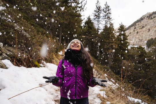 Cheerful Woman Under Falling Snow In Nature